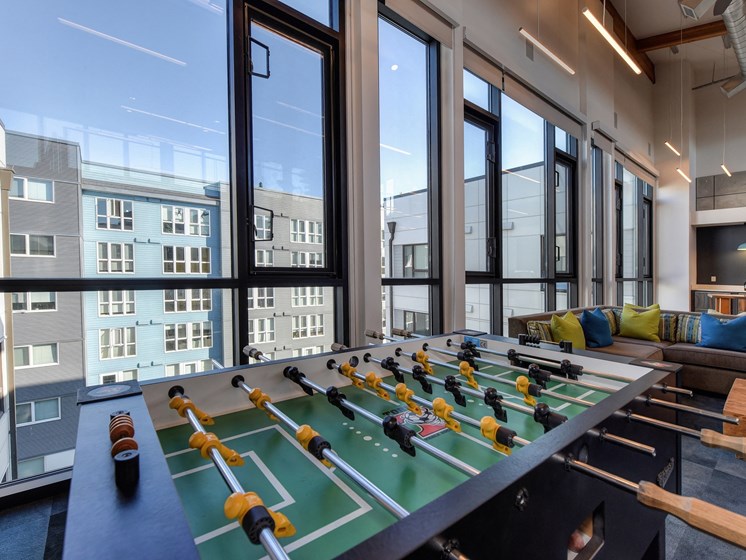 Community Clubhouse Foosball Table with View of Outside Apartment Exteriors through Large Window